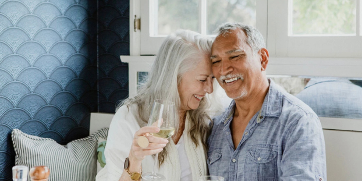 Elderly couple laughing over drinks